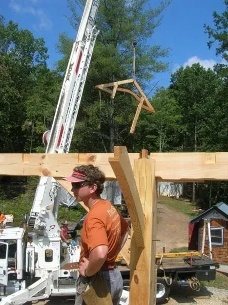 Timber frame raising with crane and craftsmen assembling post and beam structure — Virginia | Hearthstone Design Build